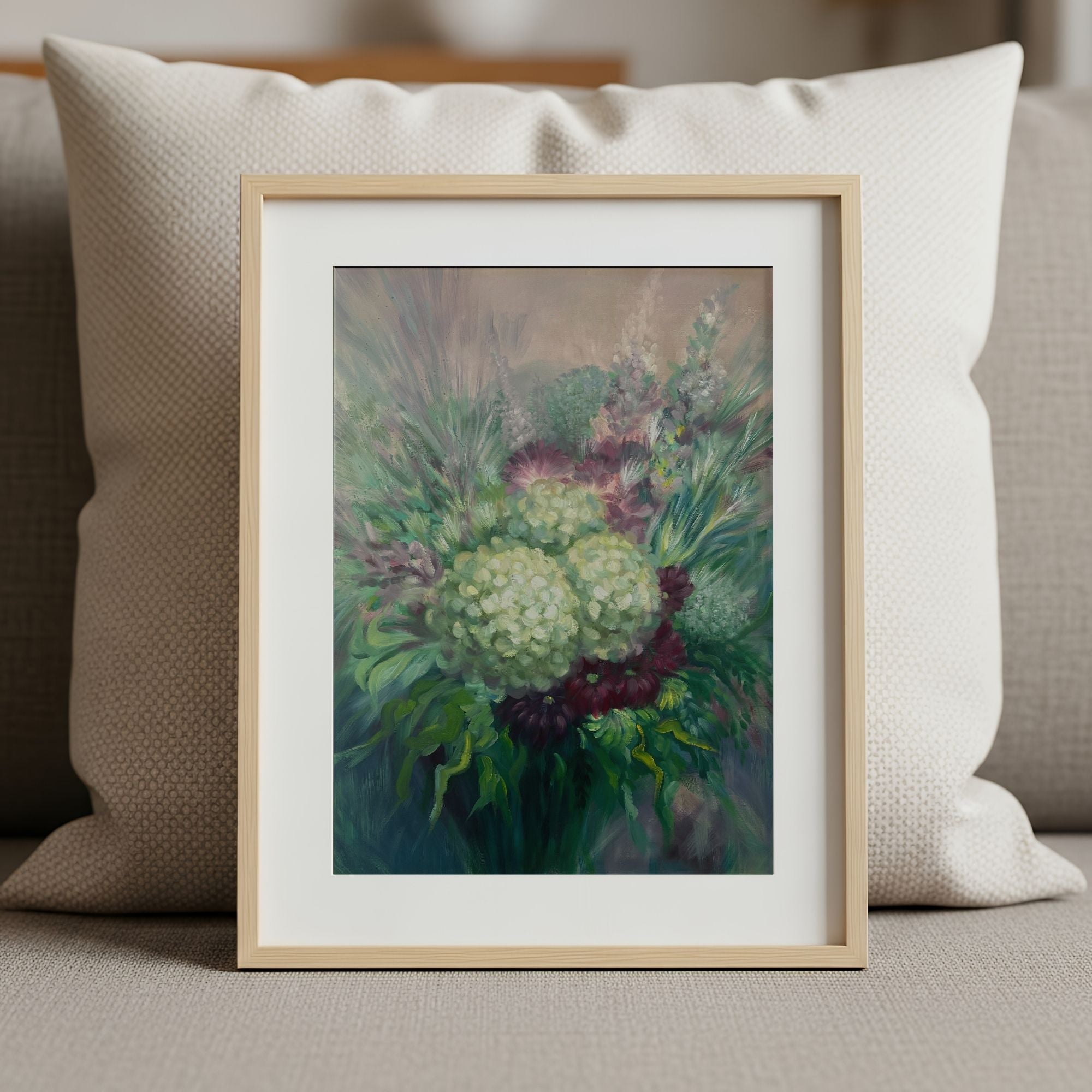 Framed art print of a floral design on a couch with a pillow.