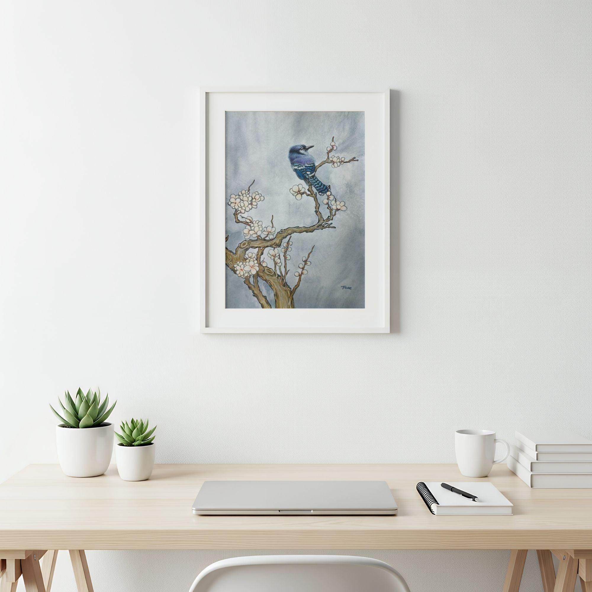 Framed artwork of a bird on a branch above a desk with office supplies, symbolizing freedom and prosperity.