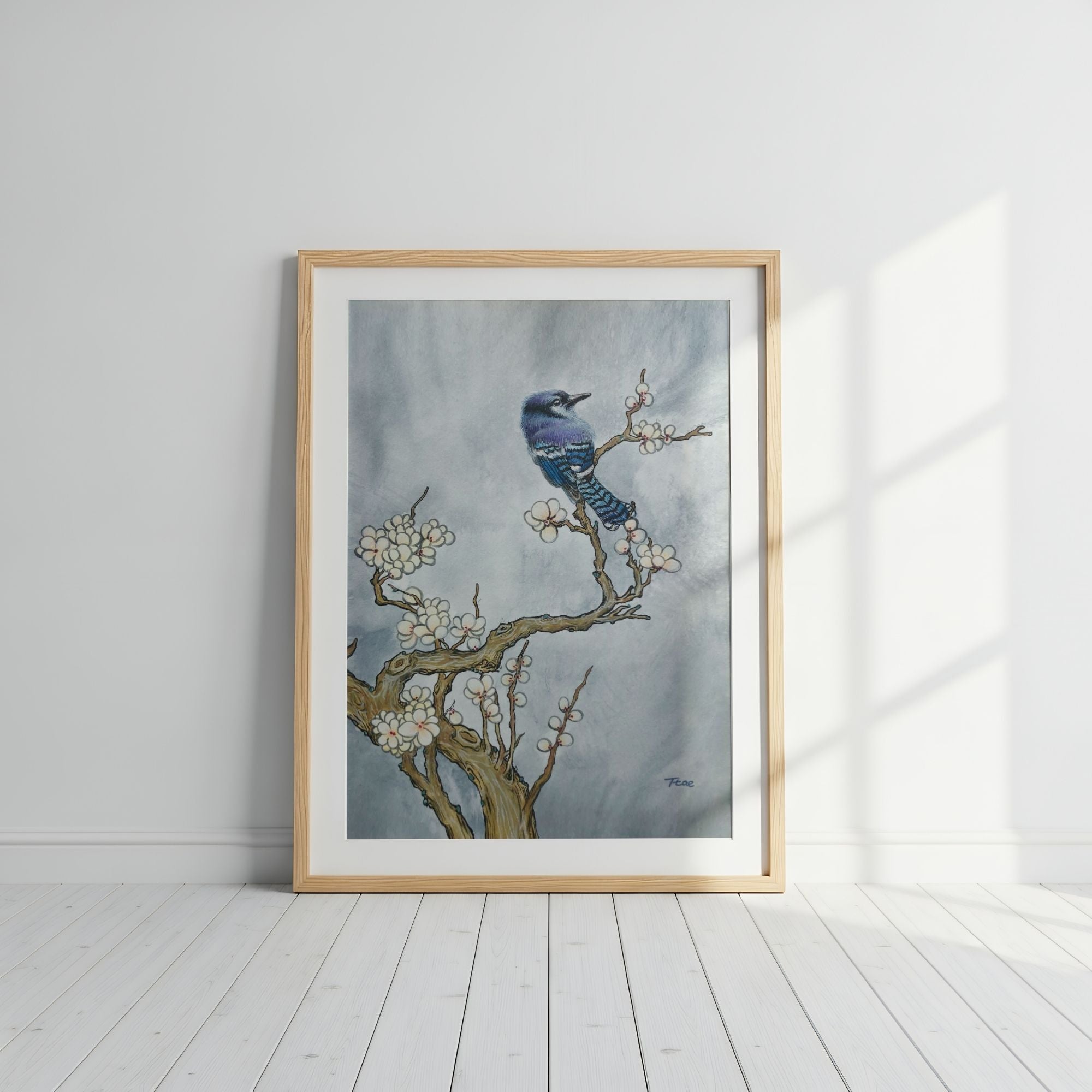 Framed artwork of a blue bird on a branch with white flowers against a gray sky, symbolizing freedom and good fortune.
