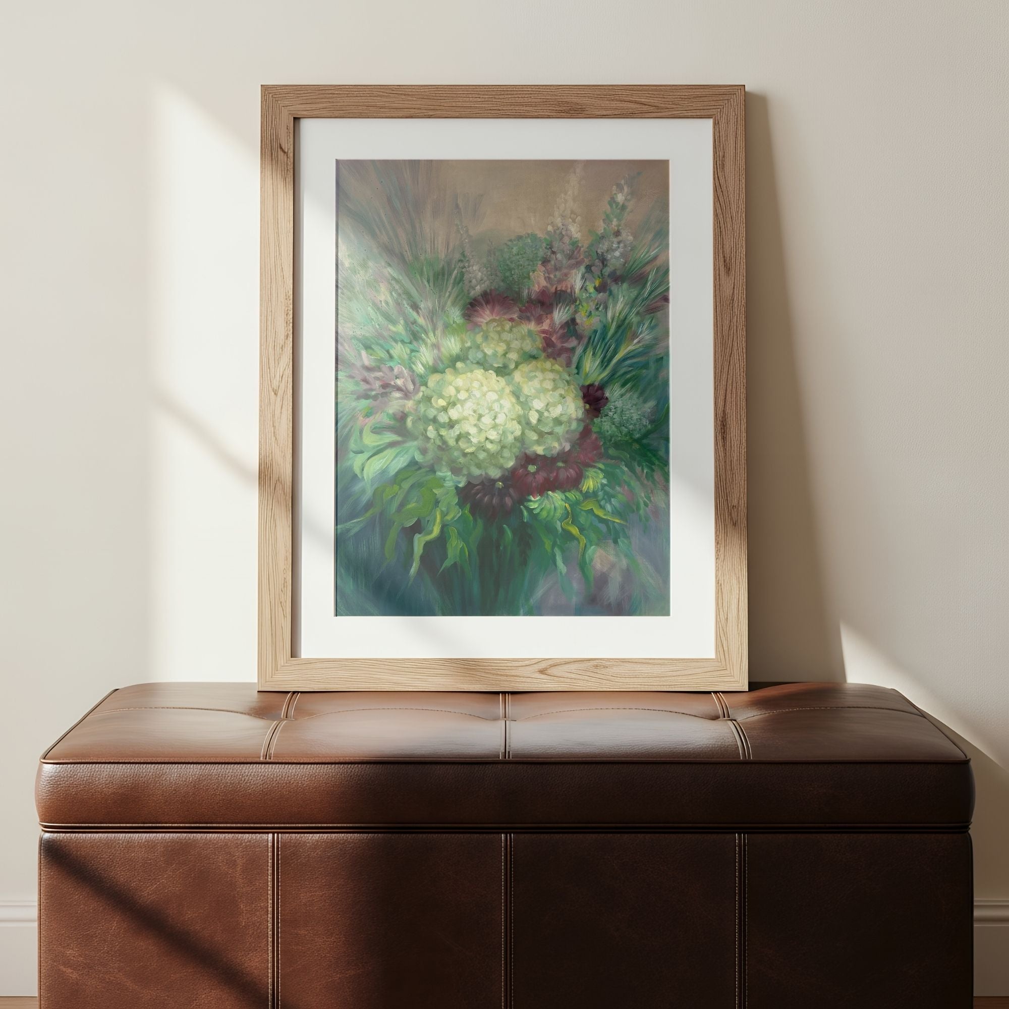 Framed art print of impressionism-style floral art on a brown leather bench against a beige wall