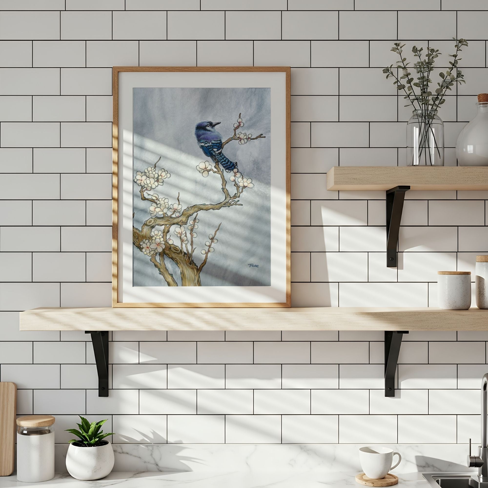 Framed artwork of a blue bird on a branch with white flowers against a gray sky, symbolizing freedom and prosperity.