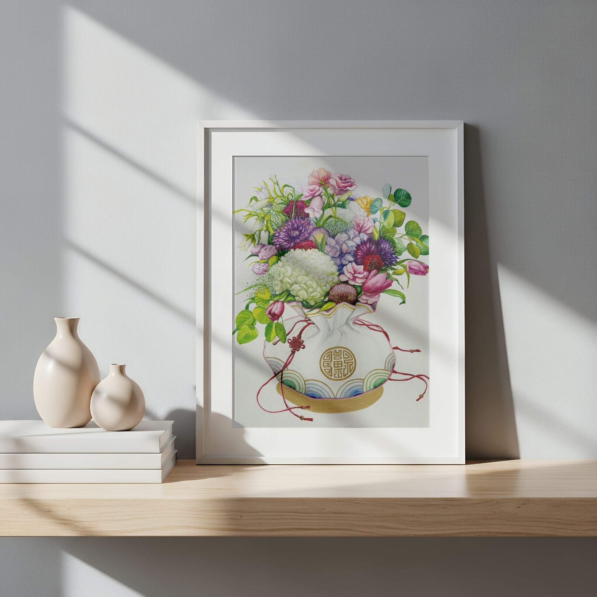 Framed wall art of a Korean coin pouch with a bouquet of flowers, which symbolizes celebrates luck, good health, and fortune, on a wooden shelf with decorative vases.