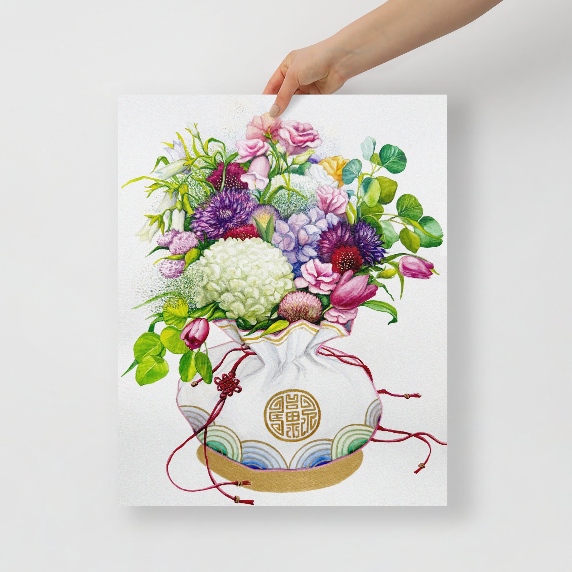 Hand holding a 16x20 inch wall art of a Korean coin pouch with a bouquet of colorful flowers, which symbolizes celebrates luck, good health, and fortune.