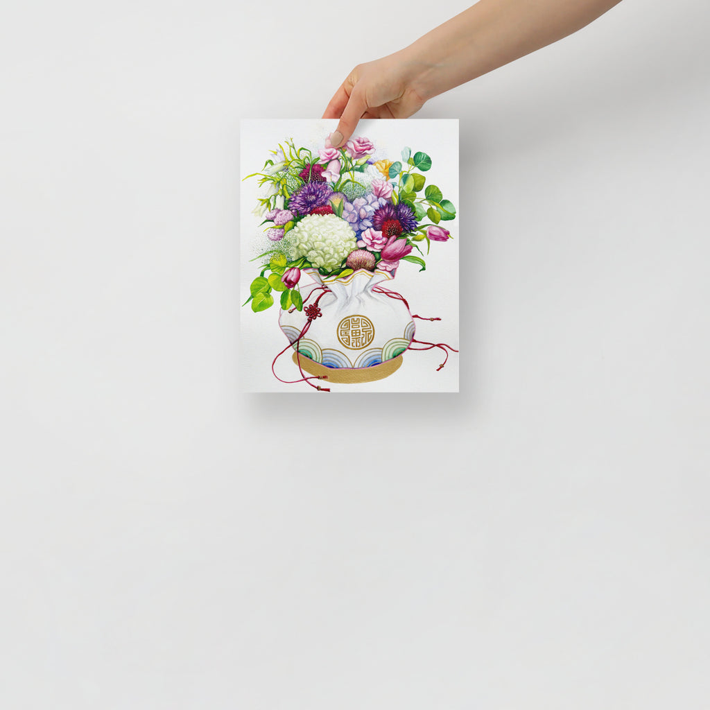 Hand holding a 8x10 inch art print of a Korean coin pouch with a bouquet of flowers, which symbolizes celebrates luck, good health, and fortune.