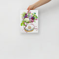 Hand holding a 8x10 inch art print of a Korean coin pouch with a bouquet of flowers, which symbolizes celebrates luck, good health, and fortune.