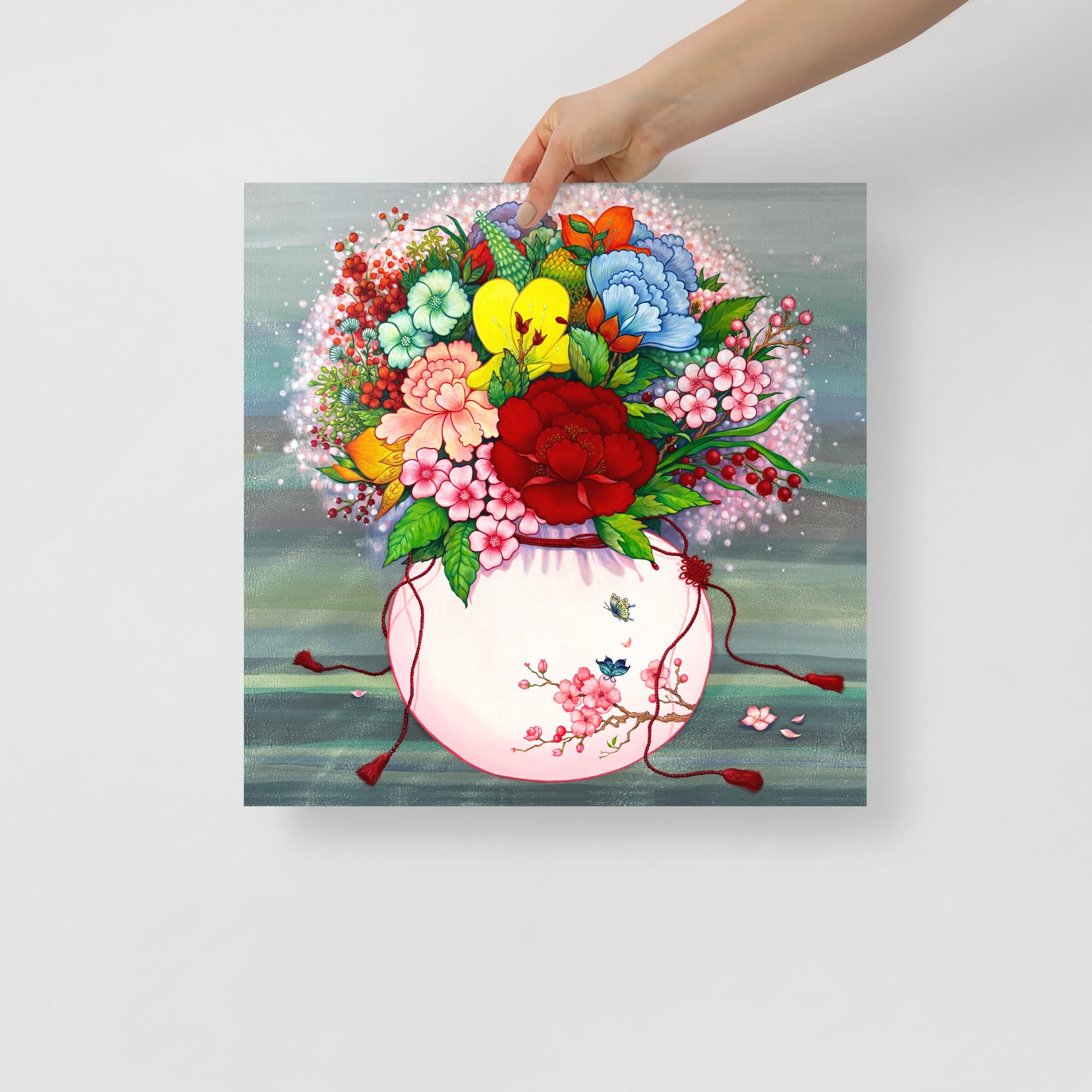 Hand holding a 16x16 inch square wall art that draws from Korean folk art heritage, weaving together blossoms and traditional motifs that celebrate harmony, wellness, and good fortune.