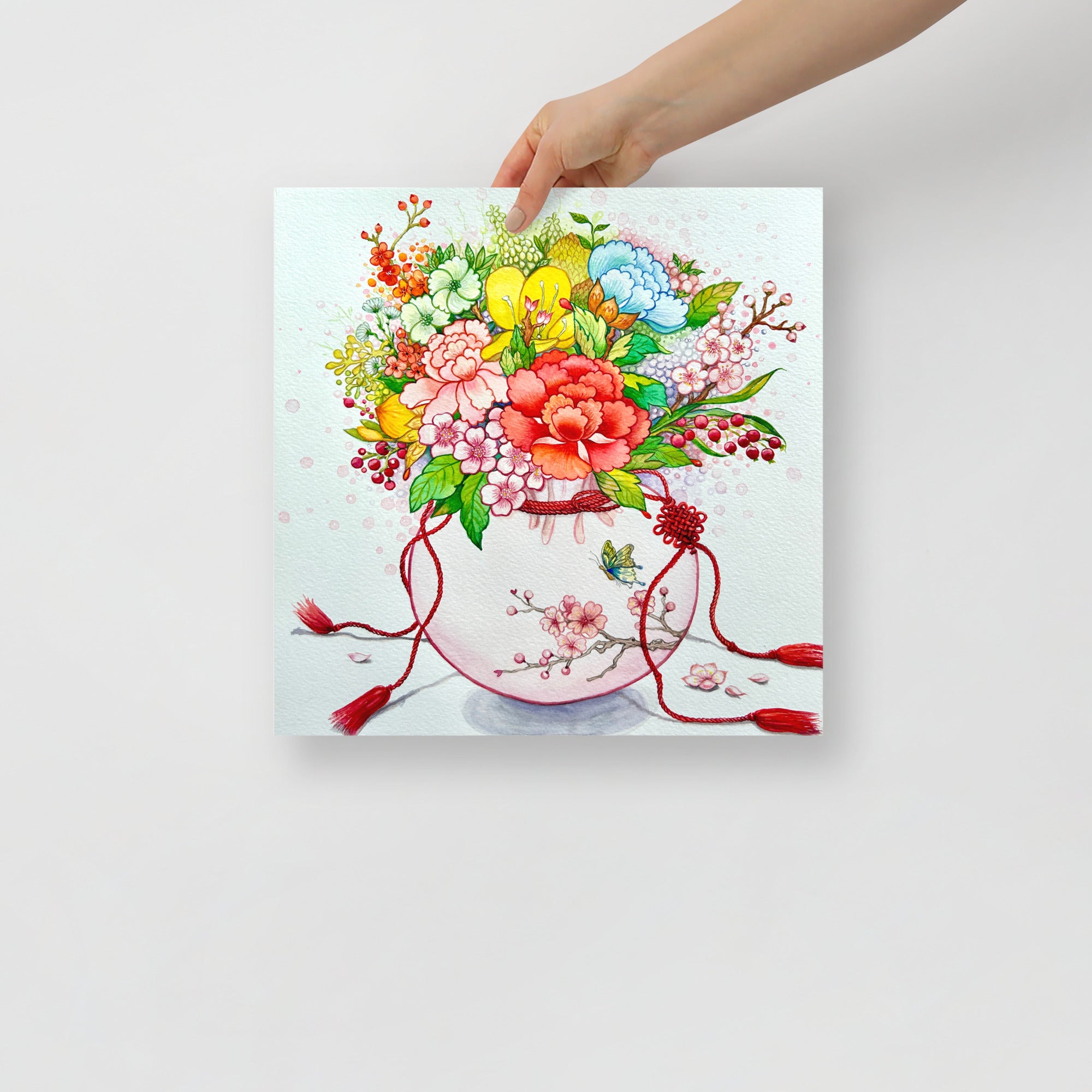 Colorful floral arrangement on an art print held by a hand against a white background (14x14 size).